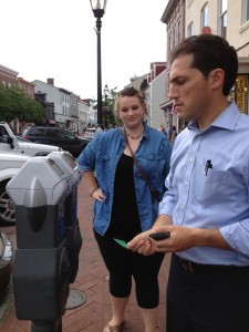 Mayor Cohen shows Maggie Lear how to use the new parking meters and pays for her parking with his credit card.