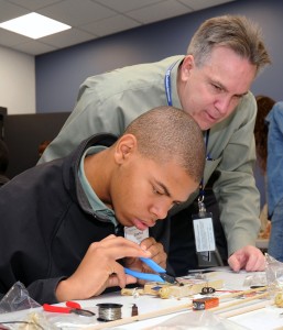 Systems Engineering Manager Mark Strickenburg assists Joshua Lewis with his radio build as part of the Northrop Grumman STEM event.